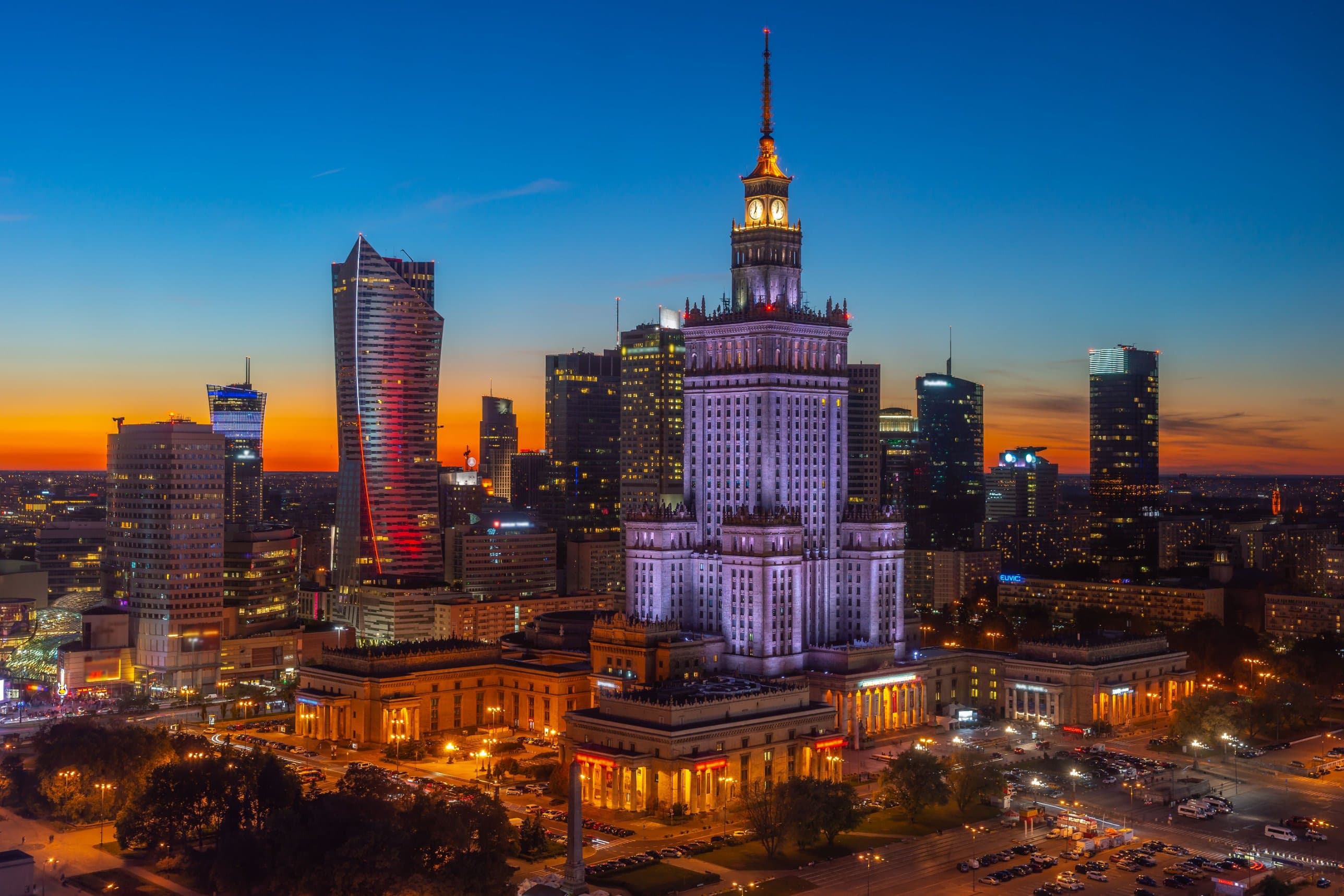 Panorama Warszawy o zmierzchu: oświetlony Pałac Kultury i Nauki na tle wieżowców centrum