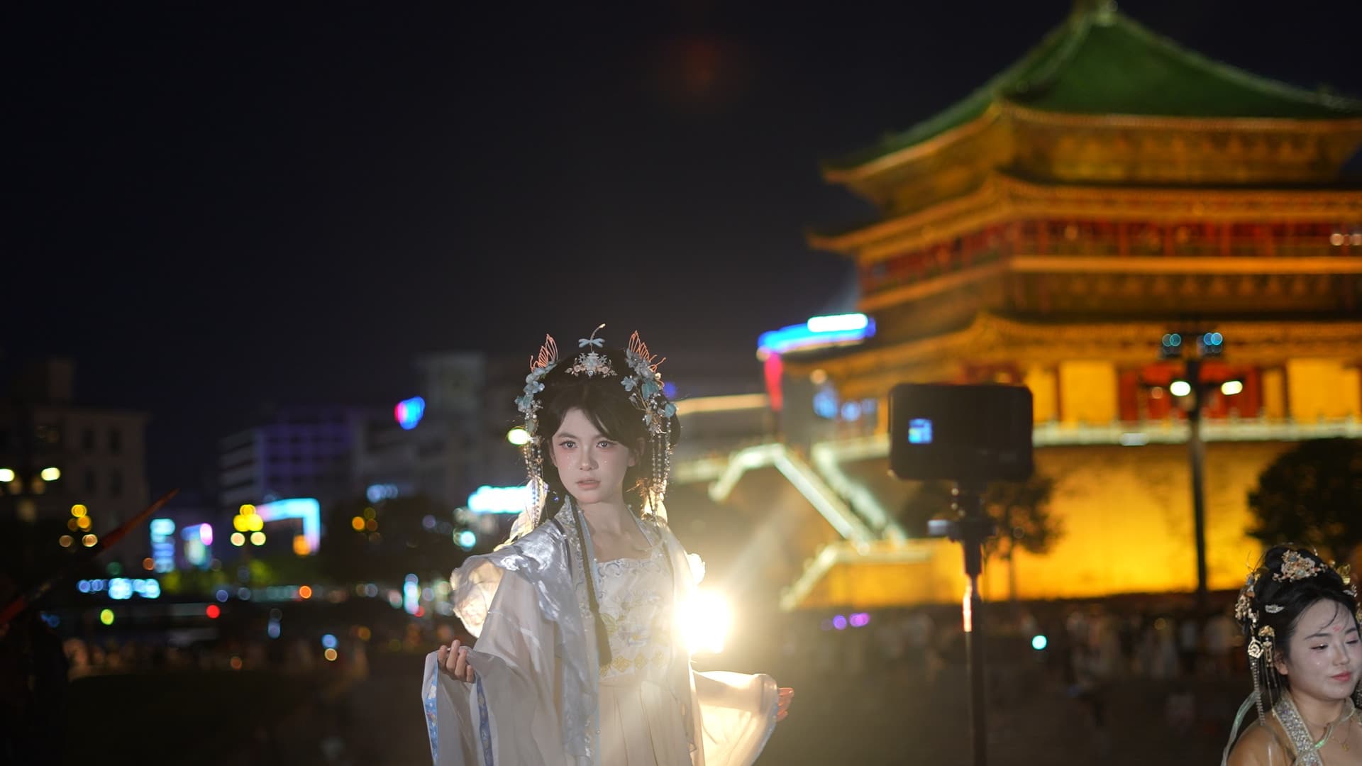 Kobieta w tradycyjnym stroju hanfu na tle oświetlonej nocą wieży w Xi’an